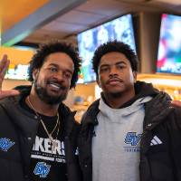 Two gentleman at event giving the "Anchor Up" sign for the camera